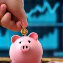 Mano depositando una moneda en una alcancía con gráficos de finanzas al fondo.